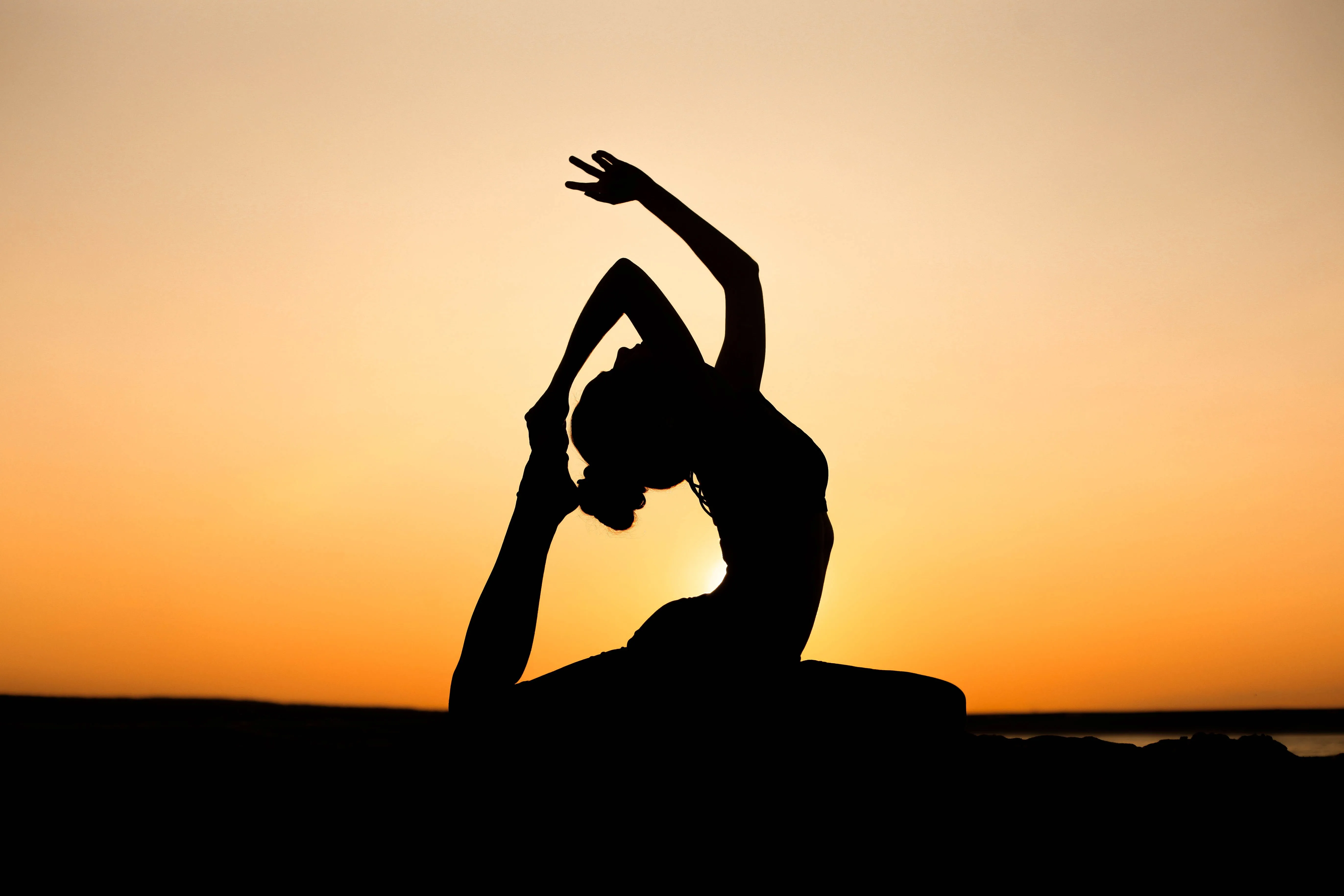 A person practising yoga at sunset